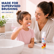 Child brushing with strawberry foam toothpaste under adult supervision