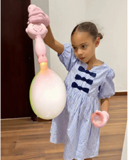 Child holding a pink smoke bubble machine with a large smoke-filled bubble indoors