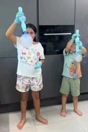Two children wearing gloves using blue smoke bubble machines indoors